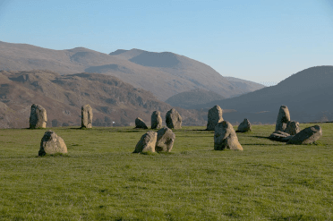 With Blencathra as an impressive backdrop, a large number of standing stones form a circle on a grassy slope in the Lake District.