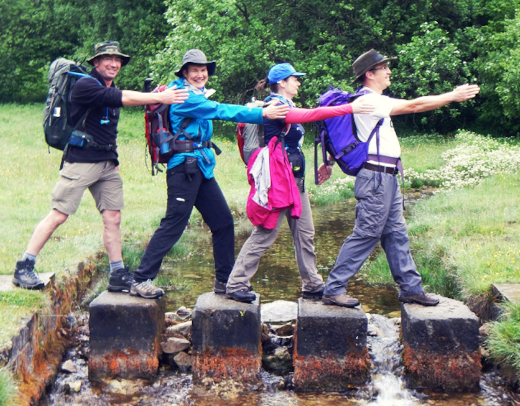 Contours customers have fun on a set of stepping stones set in a river.