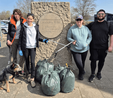 The Contours litter-picking team pose triumphant with three full bags of litter at the stone Carsington Reservoir sign.
