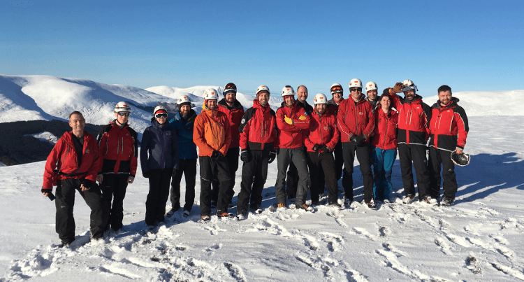 The Mountain Rescue team line up on snowy ground.