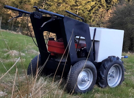 A petrol-powered wheelbarrow ferries in a plastic jug.