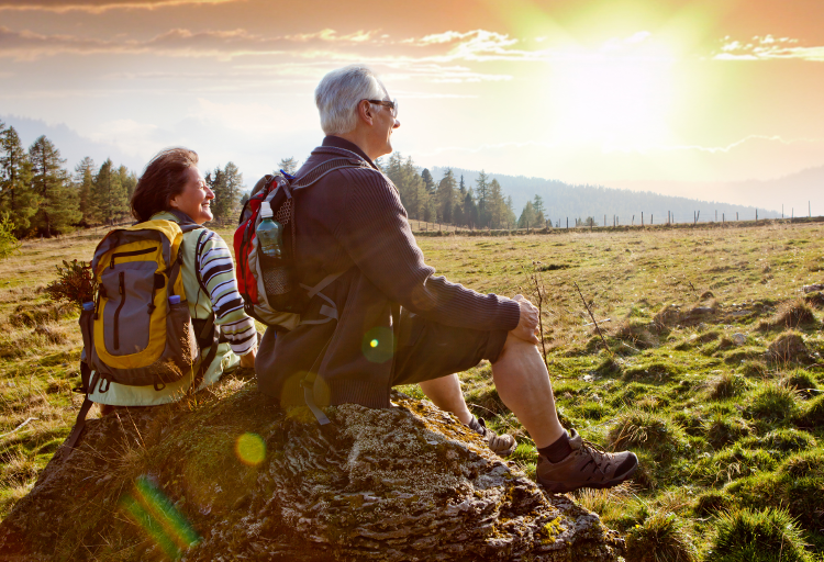 Two walkers wearing well-fitted packs enjoy the sunshine on their walk.