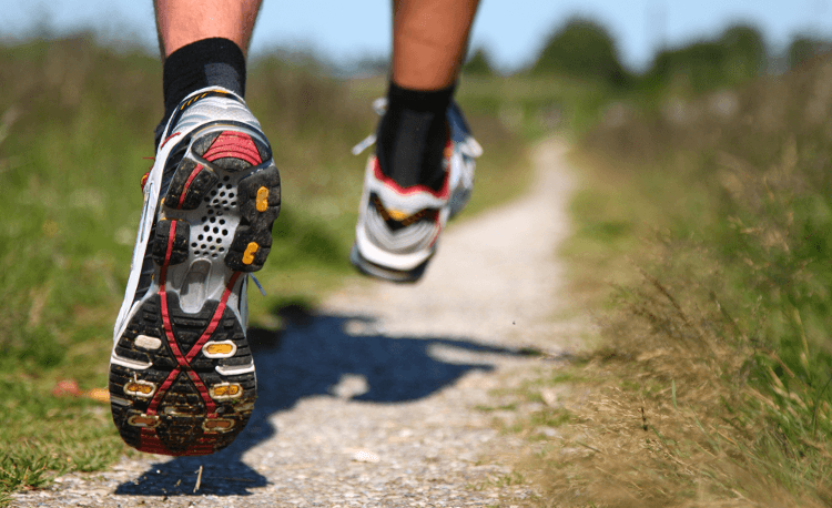 A runner in well-fitting shoes races along a trail, both feet off the ground mid-stride.