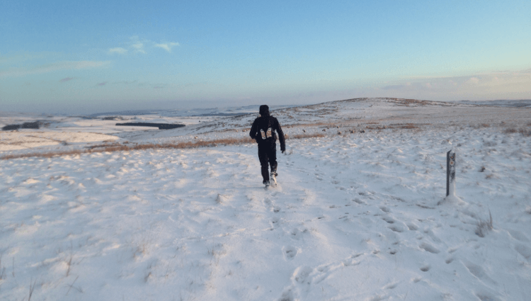 A runner jogs through snow on the Pennine Way as they compete in the Montane Spine Race.