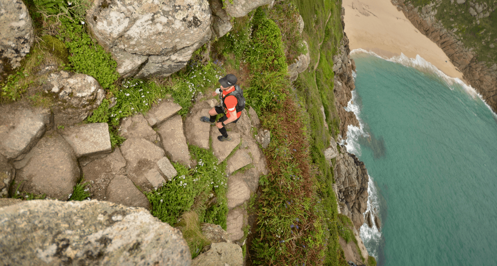 A walker follows a walking path above views over hills.