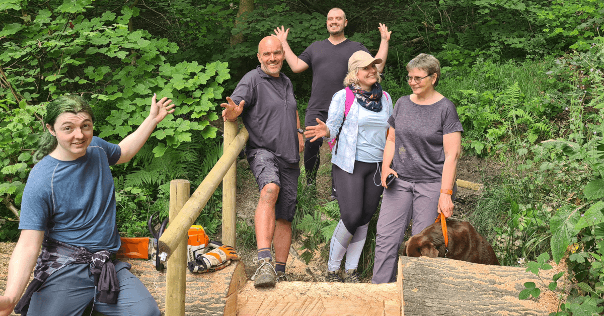 The Contours Holidays team pose atop our finished work: a useful step and handrail cut into a fallen tree.